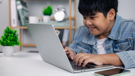 Happy young boy learning with laptop at desk, symbolizing modern education, remote schooling, and the future of digital learning for children.の写真素材