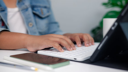 Close up of hands typing on wireless keyboard with tablet on desk, concept of freelance work, online...
