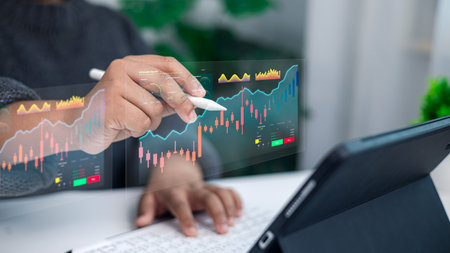 Businessman hand using digital pen analyzing stock market data and financial graph on futuristic screen with tablet computer for investment and trading concept.の写真素材