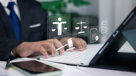 Business lawyer in suit typing on laptop with digital justice icons, law documents and gavel,...