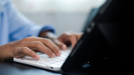 Close-up of hands typing on a tablet keyboard, symbolizing online learning, remote work, digital...