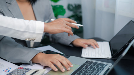 Close-up of business team collaborating and discussing project on laptop and tablet, concept of teamwork, digital strategy, and modern business communication.の写真素材