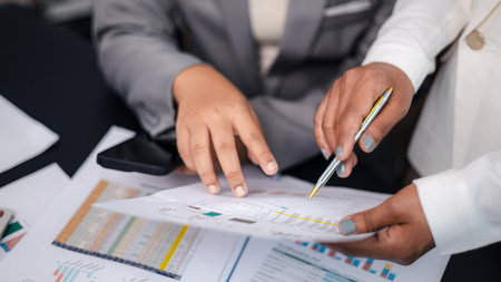 Close-up of business team discussing financial charts and data reports, concept of teamwork, business analysis, and digital strategy planning in modern office.の写真素材