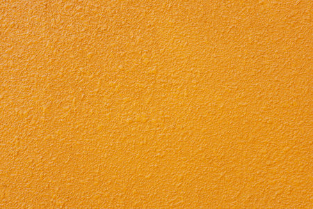 Orange wall texture with rough surface for minimal abstract background. Simple bright plaster pattern for creative design, modern architecture, and copy space concept.の写真素材