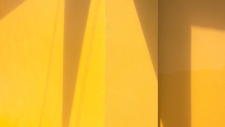 Minimal yellow wall with geometric sunlight shadow. Modern abstract architecture background for design, creative layout, and aesthetic presentation.の写真素材