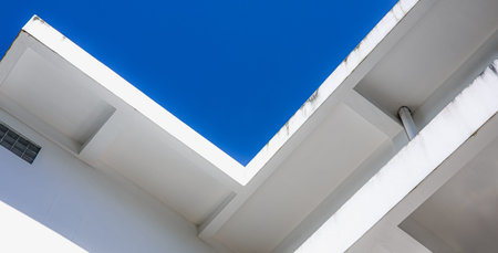 Abstract minimal architecture of modern white building with clean geometric lines and bright blue...