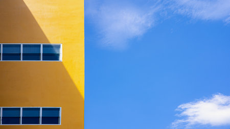 Minimal architecture with yellow wall and blue sky background, modern building design showing simplicity, geometry, and colorful urban aesthetic.の写真素材