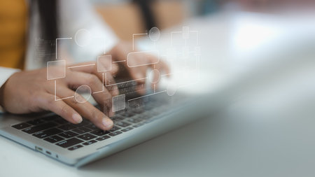 Close up of person hands typing on laptop keyboard with digital flowchart and coding script. Concept...