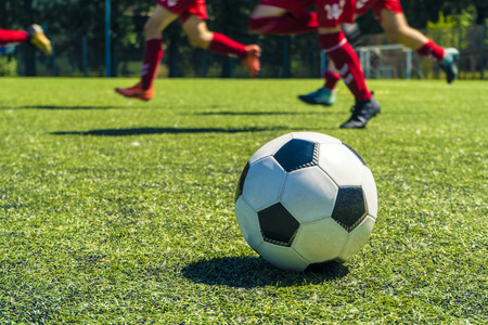 Out of focus shot of soccer balls and legs of soccer players during a soccer training session on green natural soccer pitch.の写真素材