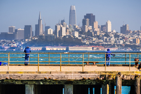 People fishing from one of the piers facing the San Francisco downtown; the city's financial district skyline visible in the background; Californiaのeditorial素材