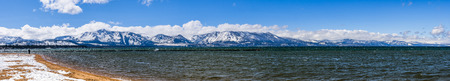 South Lake Tahoe shoreline and snow covered sandy beach, on a sunny day; the snow covered Sierra mountains in the background; Californiaの写真素材