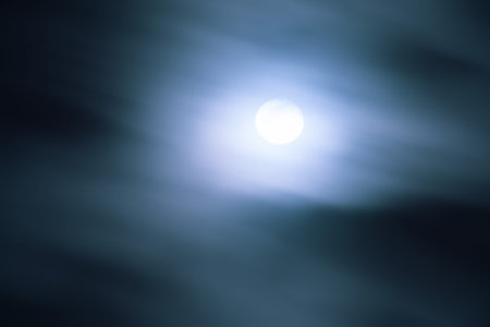 Full moon shining behind fast moving clouds; movement blur