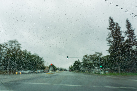 Raindrops on the windshield on a rainy day, traffic light background, Californiaの写真素材