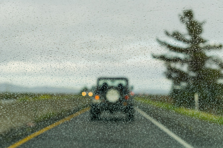 Raindrops on the windshield while driving on a freeway on a rainy day, Californiaの写真素材