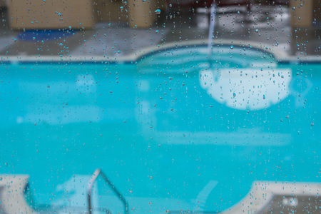 Rain drops on the window, blurred blue pool water in the backgroundの写真素材