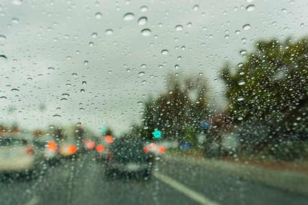 Raindrops on the windshield on a rainy day, traffic light on the background, Californiaの写真素材