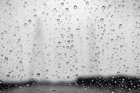 Raindrops on the window on a rainy day; abstract shapes in the background; black and white