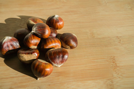 Sweet raw chestnuts on a cutting board close up; Food background for autumn