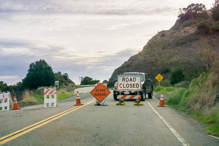 "Road closed" and "Slide Ahead" signs posted at the south side of Big Sur, Ragged Point, Californiaの写真素材