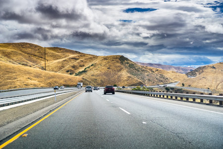 Driving through the golden hills of California in the San Luis Reservoir State Recreation area on a cloudy dayの写真素材