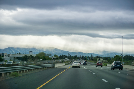March 26, 2017 San Jose/CA/USA - Driving on the freeway through Silicon Valley on a stormy spring day; rays of light and rain in the distanceのeditorial素材