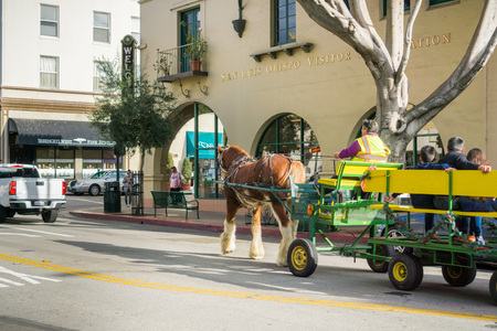 December 24, 2017 San Luis Obispo / CA / USA - Horse-drawn carriage taking people for a tour around the historical part of the city; The Visitor Information center in the backgroundのeditorial素材