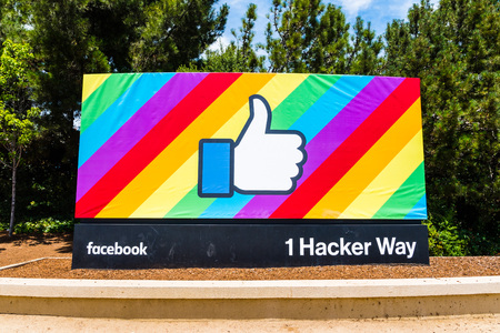 June 18, 2018 Menlo Park / CA / USA - The Facebook Like Button on a rainbow flag background, celebrating LGBTQ pride month; entrance to the company's main headquarters in Silicon Valleyのeditorial素材