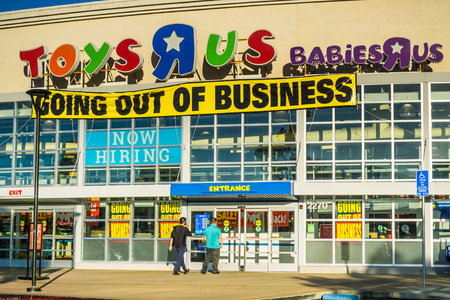 April 20, 2018 San Mateo / CA / USA - Toys R Us logo and "Going out of business" announcement above the entrance to one of the locations in San Francisco bay area; customers going into the storeのeditorial素材