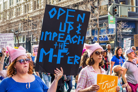 January 19, 2019 San Francisco / CA / USA - Participant to the Women's March event holds sign referencing the shutdown and impeachment while marching on Market street in downtown San Franciscoのeditorial素材