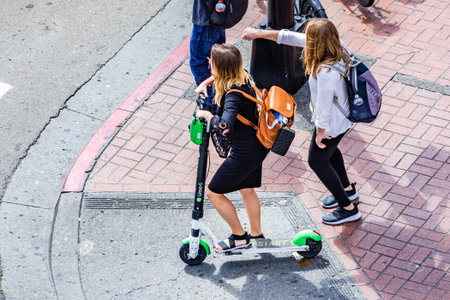 March 19, 2019 San Diego / CA / USA - Aerial view of young woman riding a lime scooter in downtown...