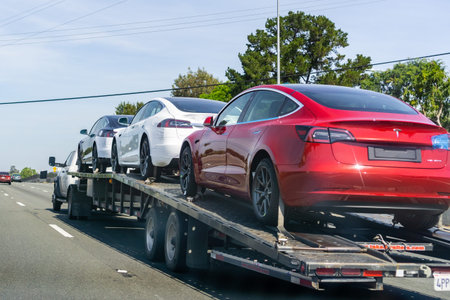 April 26, 2019 Redwood City / CA / USA - Car transporter carries Tesla Model 3 new vehicles along a...