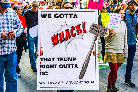 January 19, 2019 San Francisco / CA / USA - Participant to the Women's March event holds "We Gotta Whack that Trump right Outta DC" sign while marching on Market street in downtown San Franciscoのeditorial素材