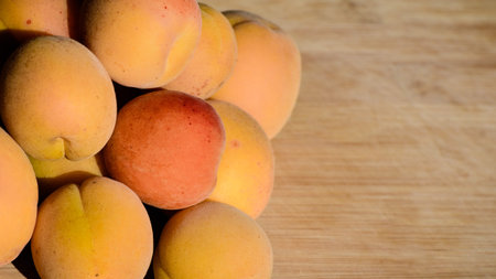 Close up of ripe Blenheim apricots freshly picked, on a wooden table; Blenheim apricots are the most...