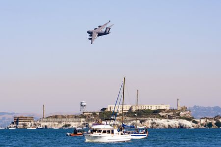 Oct 12, 2019 San Francisco / CA / USA - Boeing C-17 Globemaster III aircraft flying over Alcatraz island at the 39th Fleet Week event; people on private ships watching from below;のeditorial素材