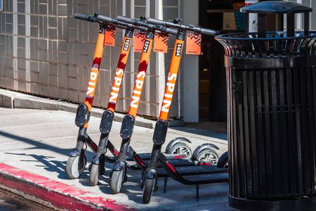 Oct 20, 2019 San Jose / CA / USA - SPIN e-scooters lined up on a sidewalk in downtown San Jose; Spin is a bicycle-sharing and scooter-sharing company that is owned by the Ford Motor Companyのeditorial素材
