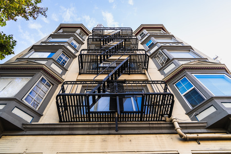Exterior view of multifamily residential building; Old metal fire escape stairs hanging on side of the building; Berkeley, San Francisco Bay Area, Californiaのeditorial素材