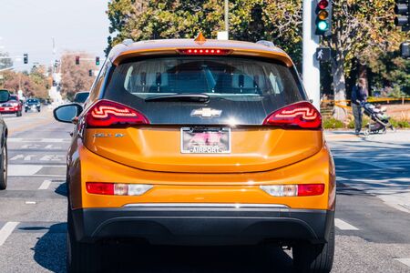 Nov 6, 2019 Mountain View / CA / USA - Chevrolet Bolt EV (in the Cayenne Orange Metallic color) waiting at a traffic stop in South San Francisco bay area; Silicon Valleyのeditorial素材