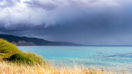 The calm before the storm; Clear and calm turquoise water on the Pacific Ocean coastline, with...