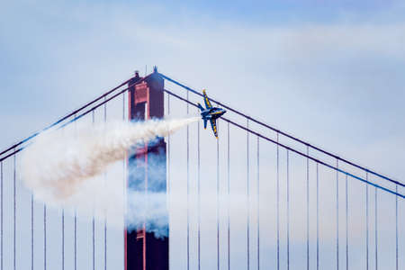 Oct 12, 2019 San Francisco / CA / USA - US Navy Blue Angels in F-18 Hornet plane performing in the Fleet Week Airshow; Golden Gate Bridge visible in the backgroundのeditorial素材