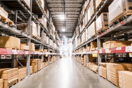 Blurred view of the interior of a warehouse; boxes stacked up high on both sides of an aisleの写真素材