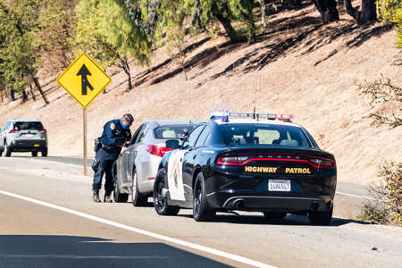 Oct 14, 2020 Fremont / CA / USA - Highway Patrol officer writing a traffic ticket to a driver pulled over on the right side of the roadのeditorial素材