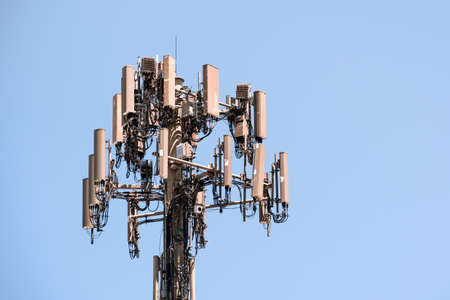 Close up of telecommunications cell phone tower with wireless communication antennas; blue sky background and copy space on the rightの写真素材
