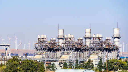 Natural Gas-Fired, Combined-Cycle Power Plant equipped with emissions control technology; Wind Turbines visible in the background; East San Francisco Bay Area, Californiaの写真素材