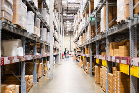 Warehouse interior view, with boxes stacked up high on both sides of an aisleの写真素材