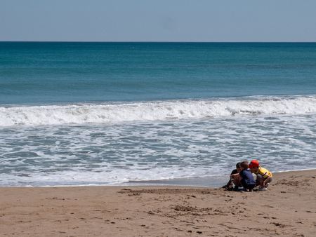 Children playing with sand in the sea making a castle in the sea with sand.の写真素材