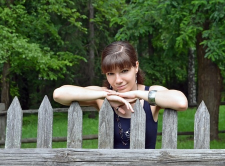 Beautiful young woman standing near vintage rural fence の写真素材