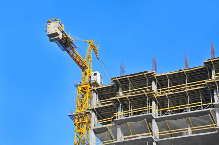 Crane and building construction site against blue skyのeditorial素材