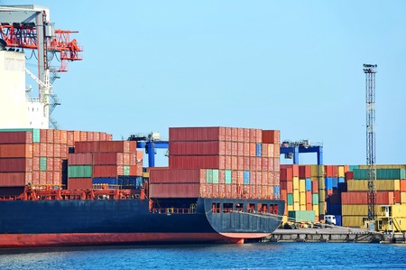 Container stack and ship under crane bridgeの写真素材