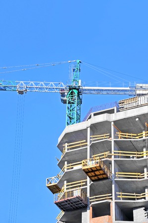 Crane and building construction site against blue skyの写真素材