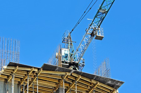 Crane and building construction site against blue skyの写真素材